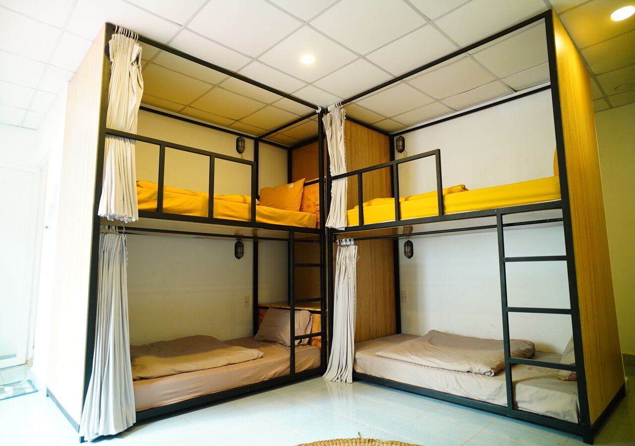 A dormitory room with bunk beds, a ladder, and curtains.