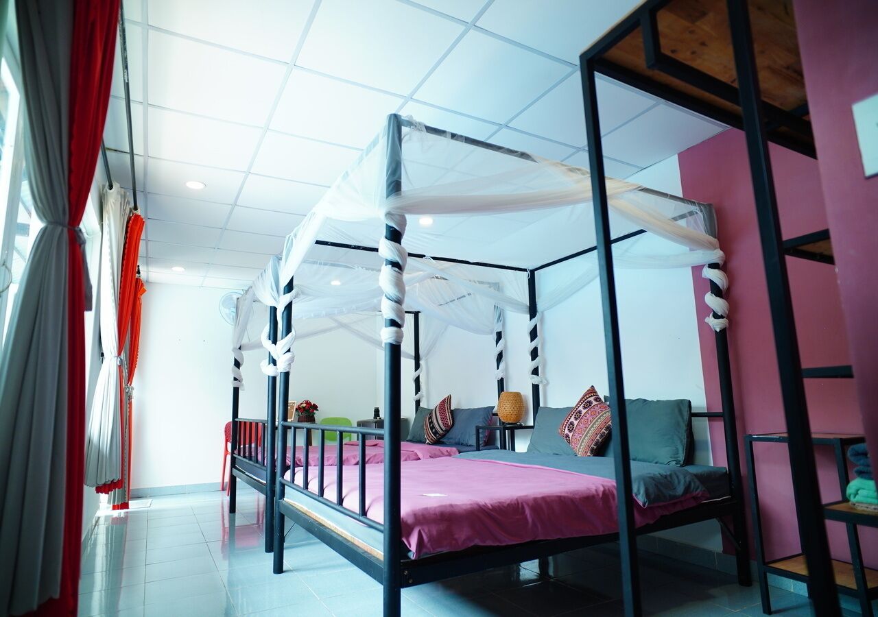 A room with a four-poster bed, a red chair, and a small table with a lamp.