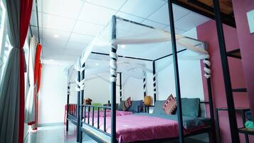 A room with a four-poster bed, a red chair, and a small table with a lamp.