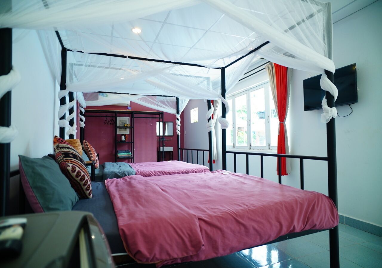 Una habitación con cama, televisor y ventana con cortinas.