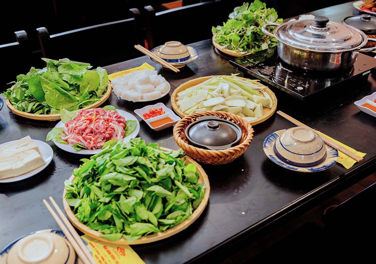 A table with various food items and a pot on a stove.