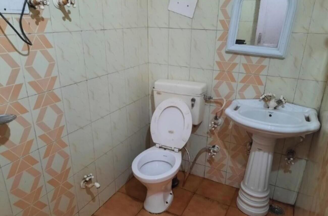 A small bathroom with a toilet, a sink, and a mirror.