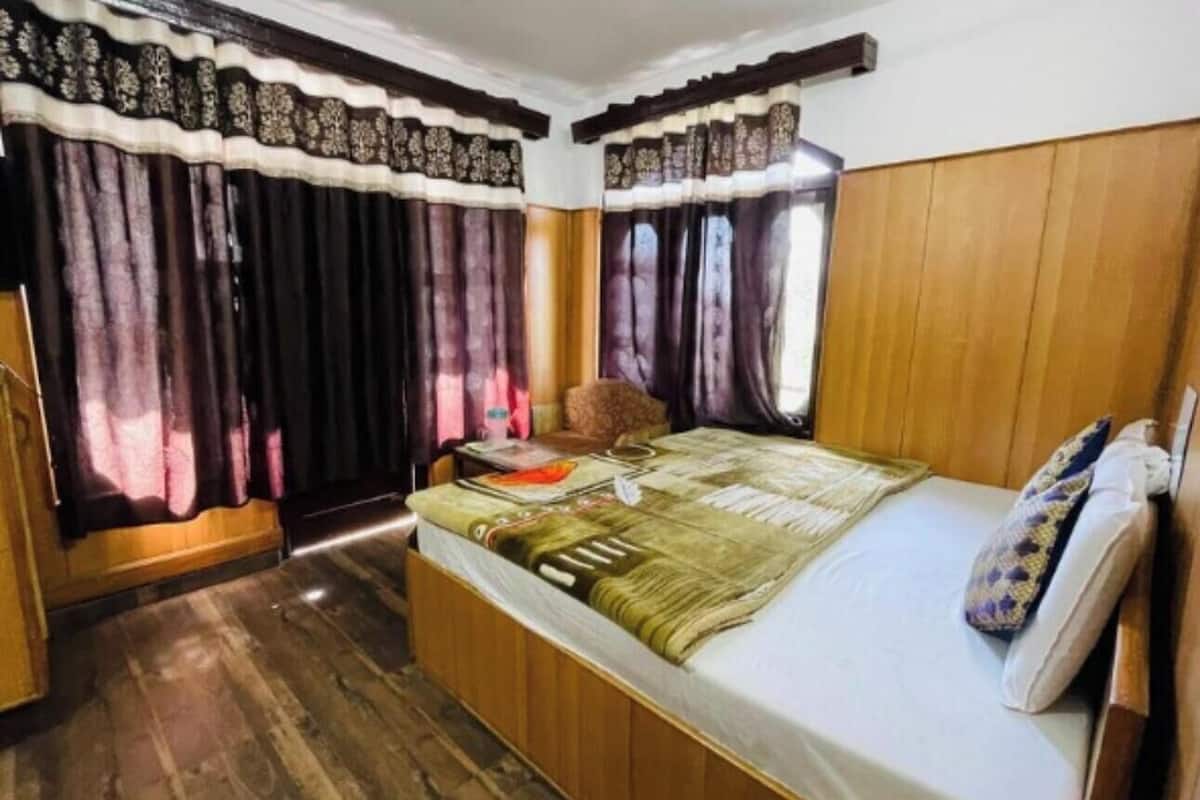 Quarto com cama de madeira, mesa de cabeceira e cortinas.