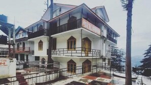 A two-story hotel with a balcony on the upper floor, a sign indicating it's open, and a red and white checkered ground floor. - Hotel Dreamland (Udhampur)