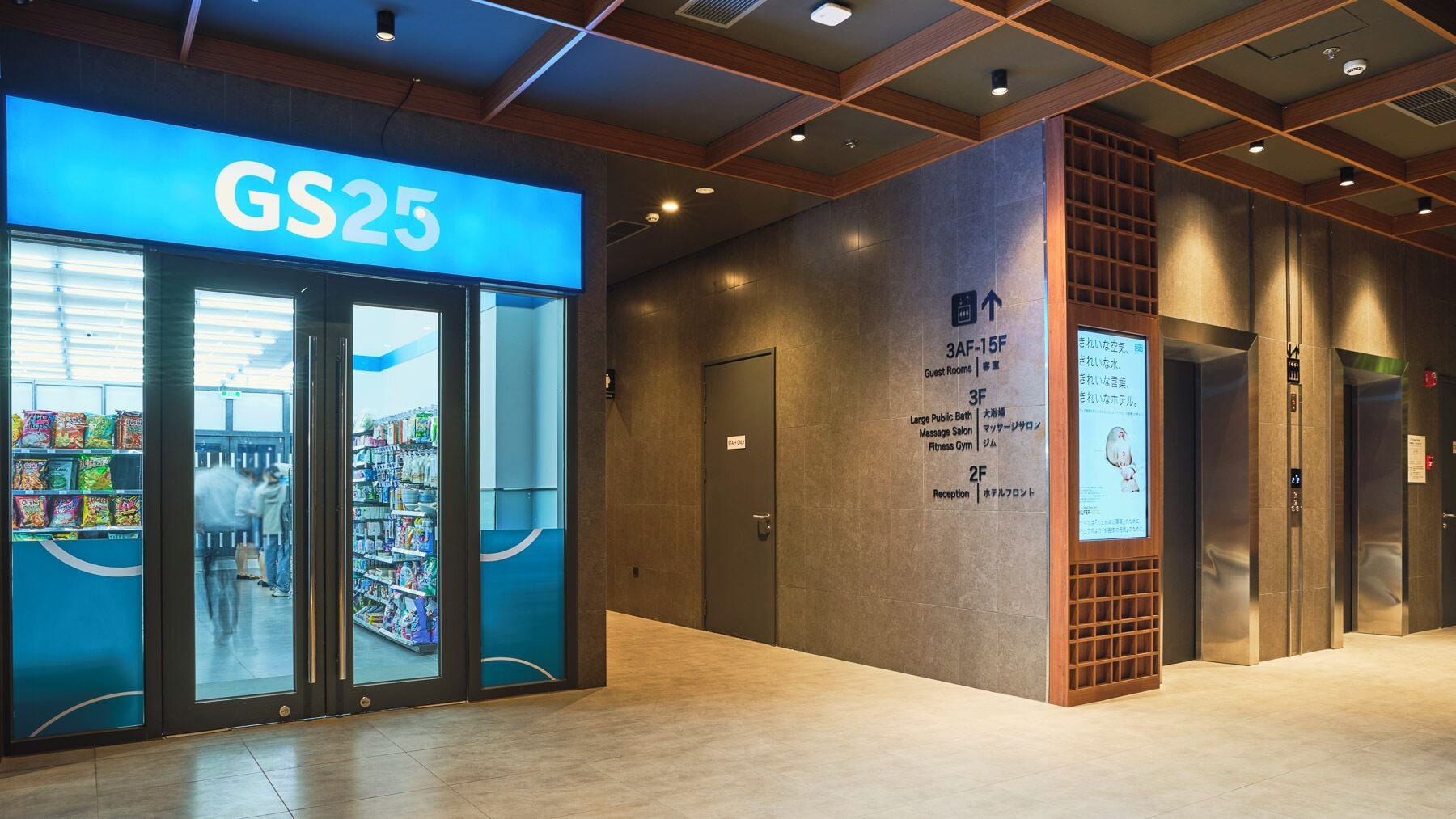 Entrada de um hotel com uma loja de conveniência GS25, área de recepção e elevador.