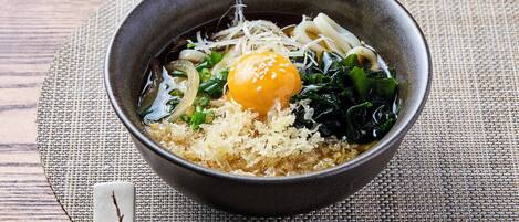 A bowl of ramen with egg, seaweed, and noodles on a woven mat.