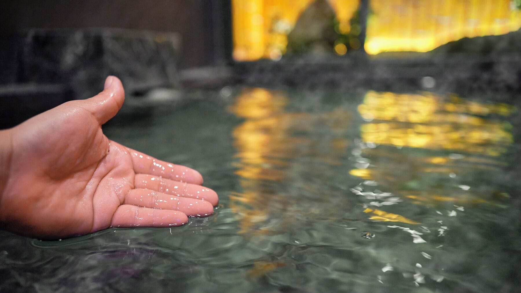 Eine Hand im Wasser, unscharfer Hintergrund.
