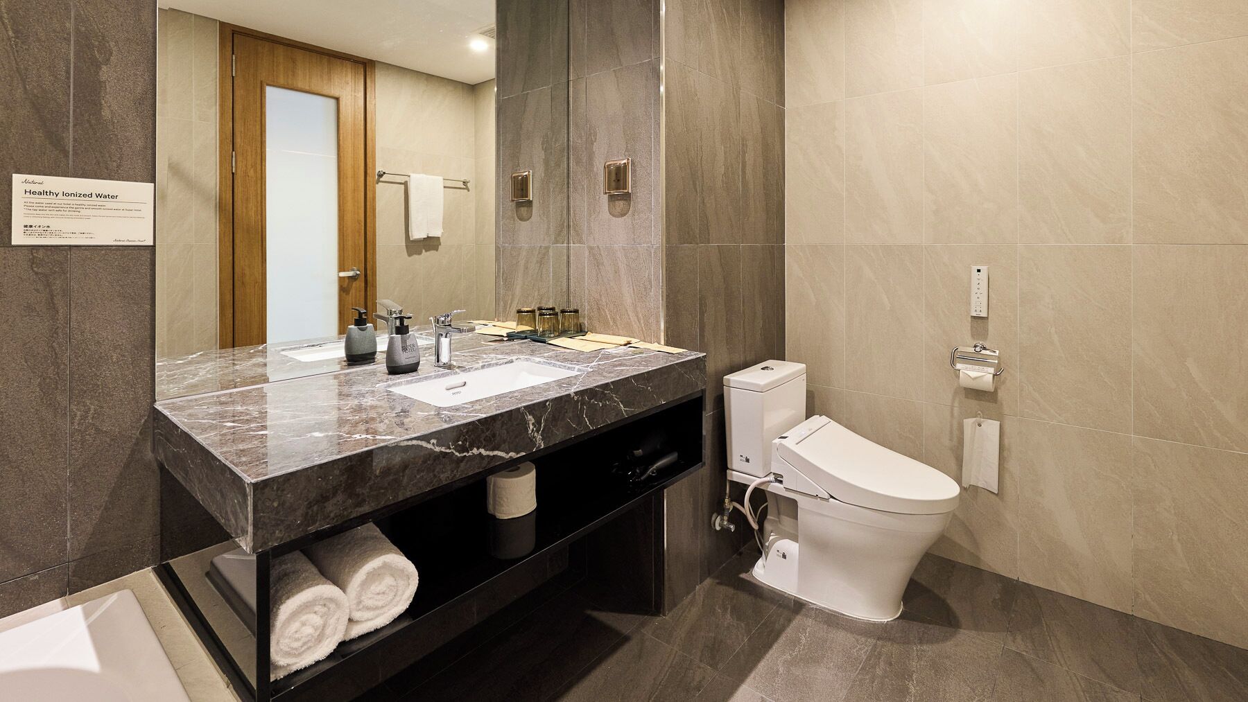 A modern bathroom with a marble sink, a toilet, and a towel rack.