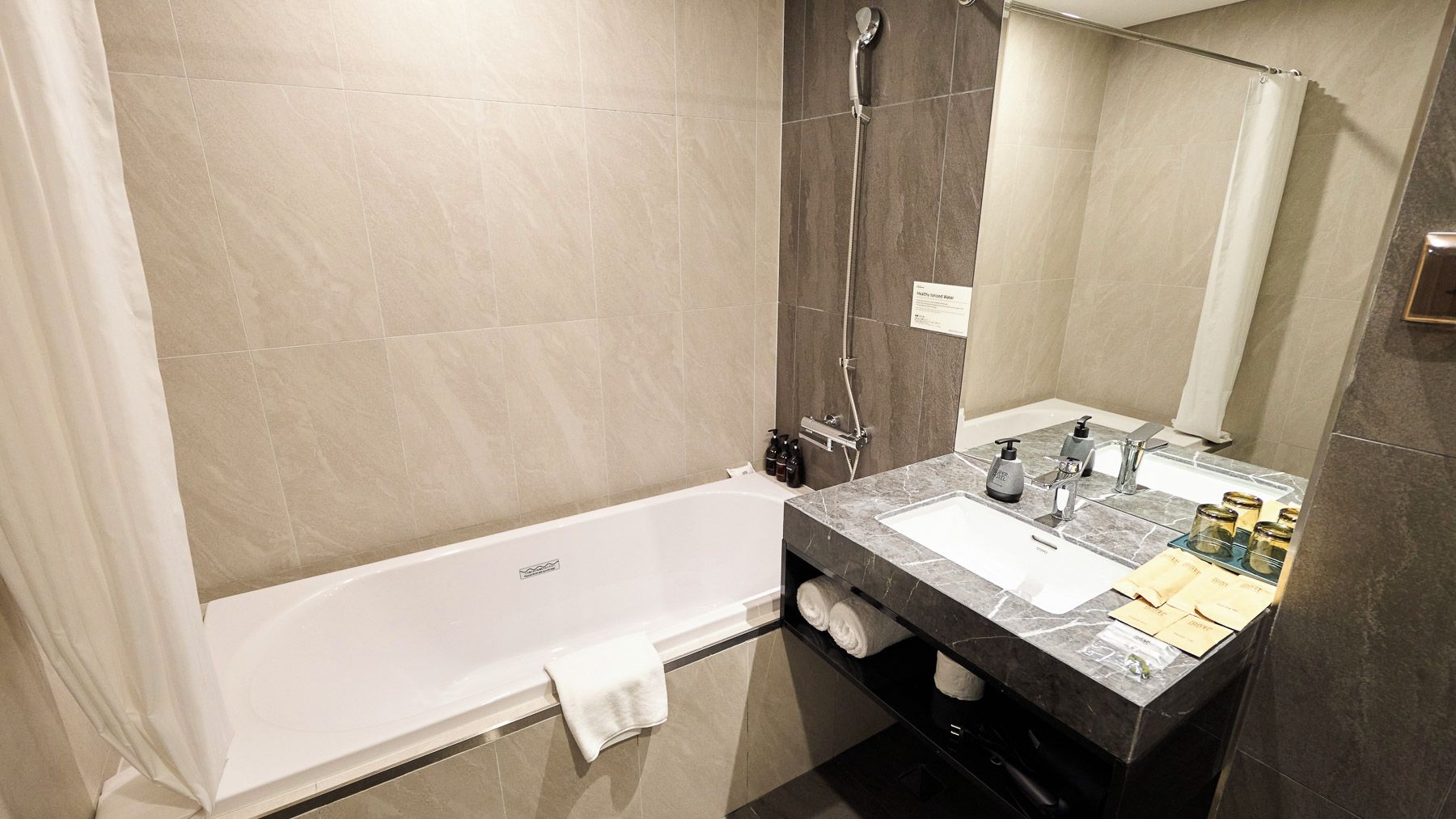 A modern bathroom with a bathtub, a shower, and a vanity with a sink and mirror.