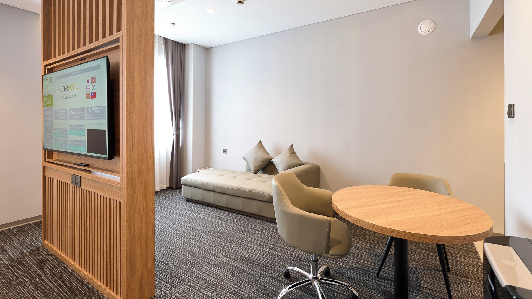 Une chambre d’hôtel équipée d’un téléviseur à écran plat, d’un canapé, de deux fauteuils et d’une petite table.