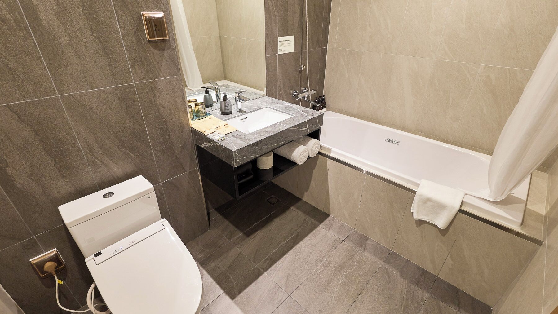 Moderni kylpyhuone, jossa on wc, pesuallas ja kylpyamme.