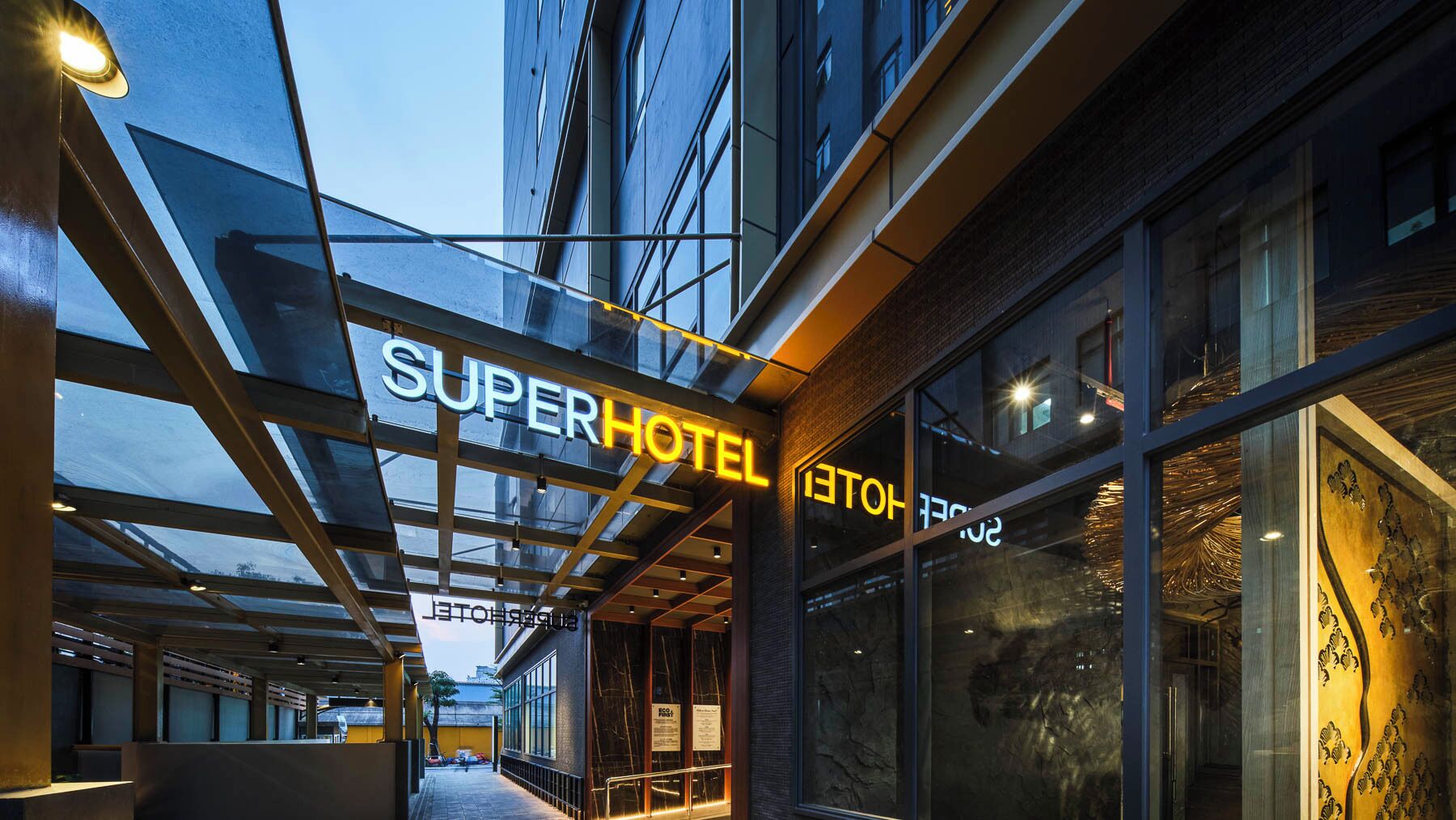 A hotel entrance with a 'SuperHotel' sign, large windows, and a modern architectural design.