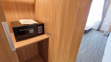 Habitación de hotel con puerta de madera, una nevera pequeña y un aviso en la puerta.