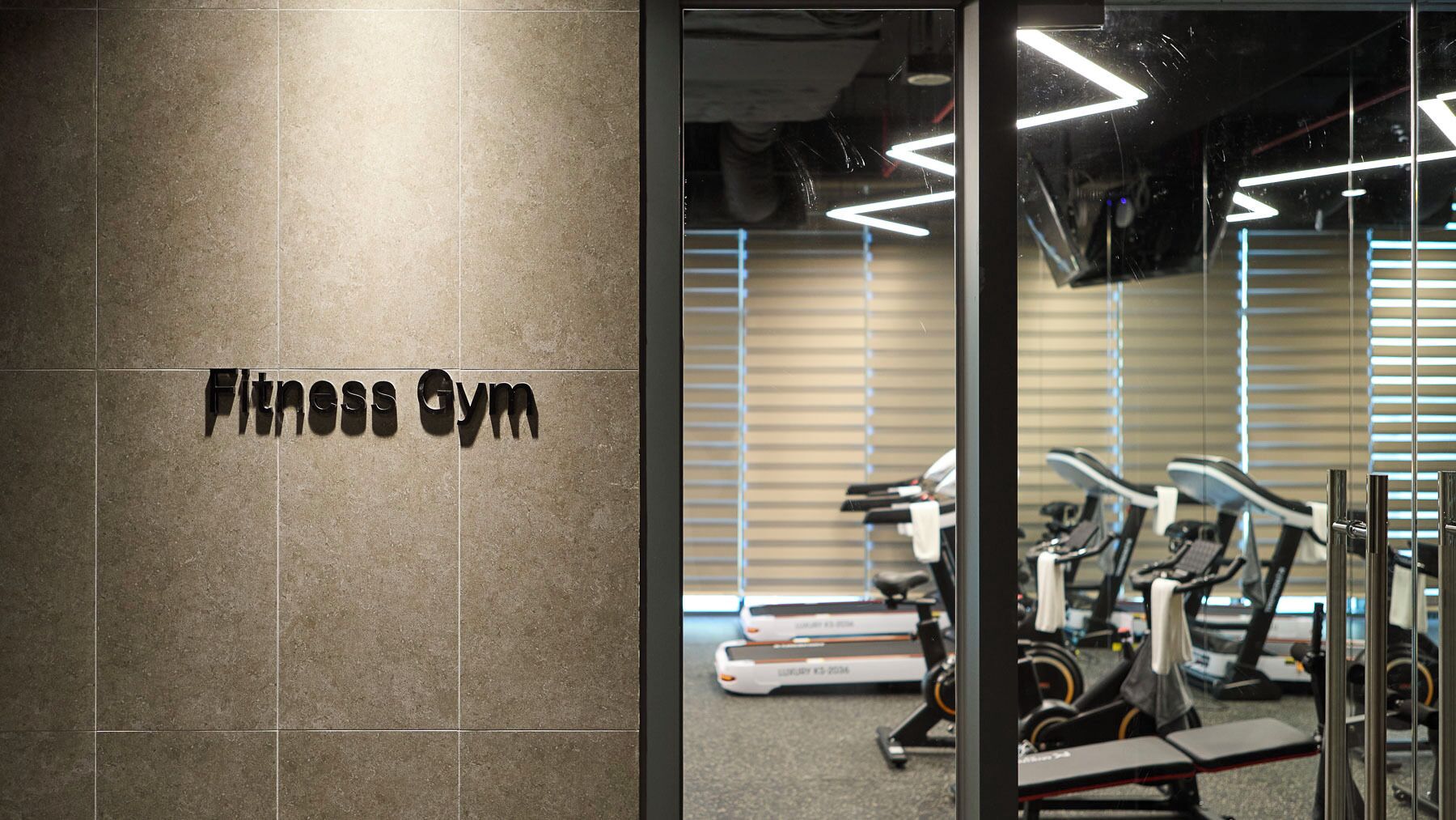 A fitness gym with exercise equipment, a wall-mounted sign, and a glass door.