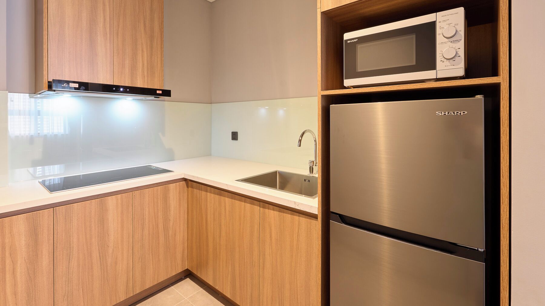 Una cocina moderna con microondas integrado, refrigerador de acero inoxidable y una encimera elegante.