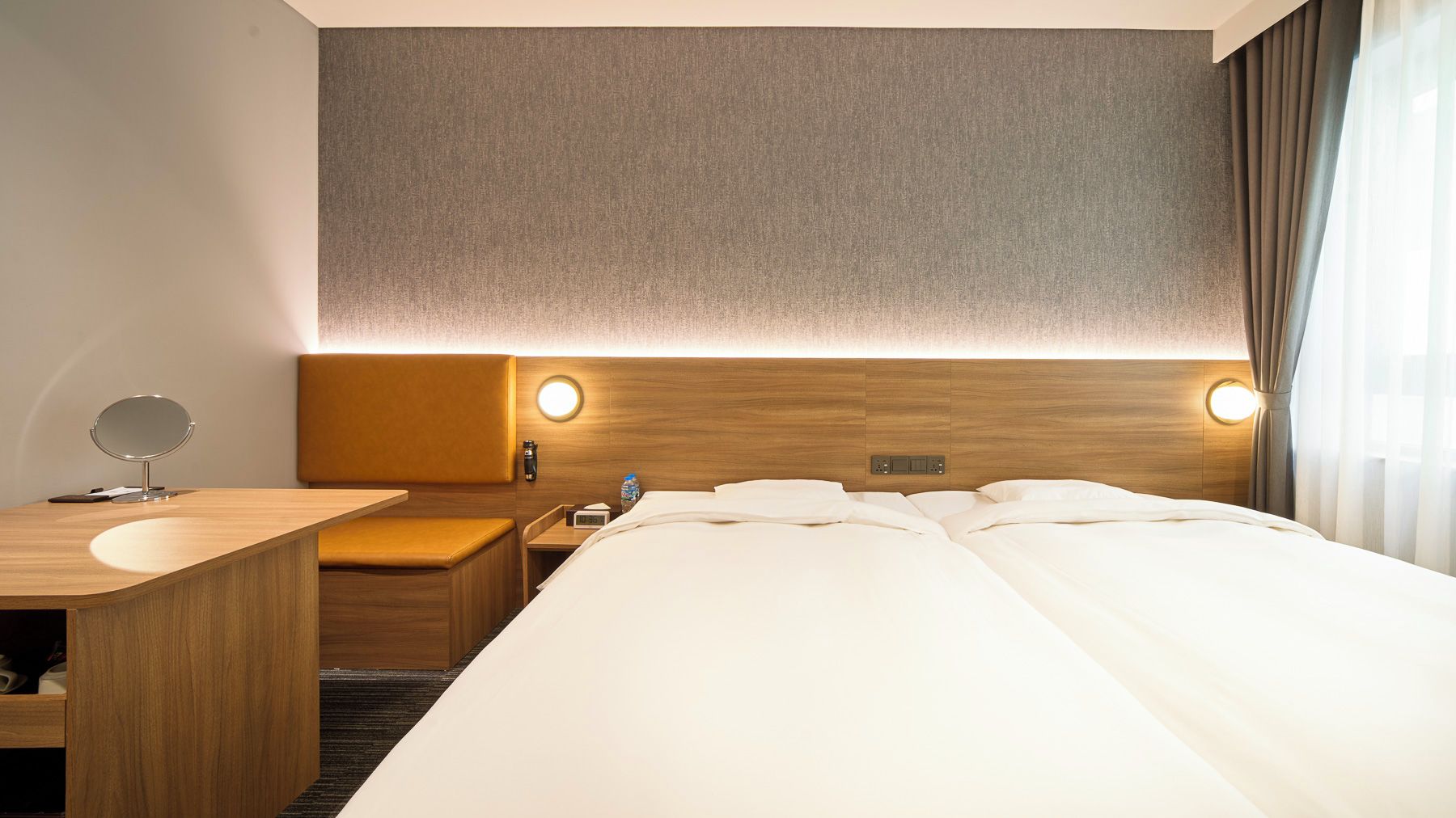 Quarto de hotel com uma cama, mesa de cabeceira e um espelho.