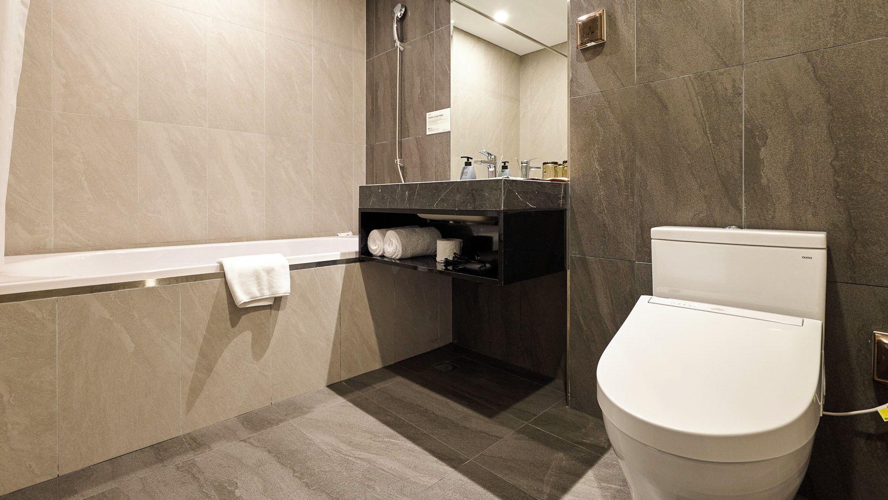 A modern bathroom with a bathtub, toilet, and a vanity with a mirror.