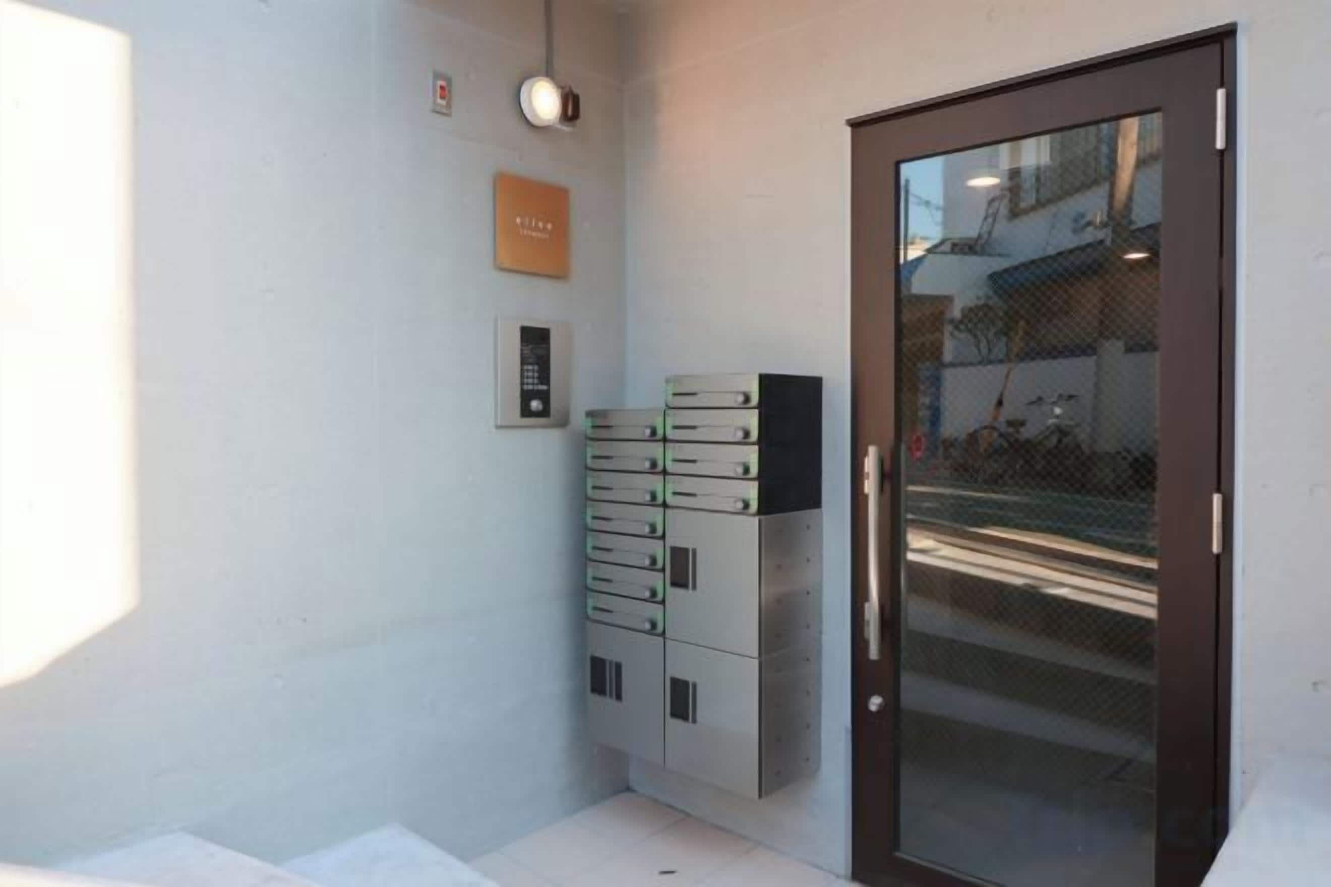 A hotel room with a door, a wall-mounted light, a security keypad, and a stack of safes.
