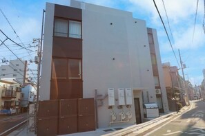 Un edificio moderno con fachada plana, ventanas amplias y entrada protegida por una reja.