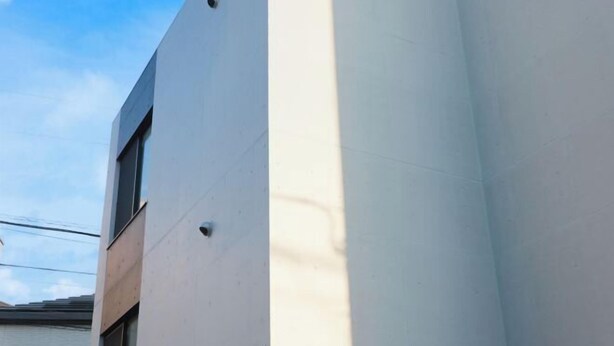 Un bâtiment moderne doté d’une façade blanche et d’une grande fenêtre verticale.