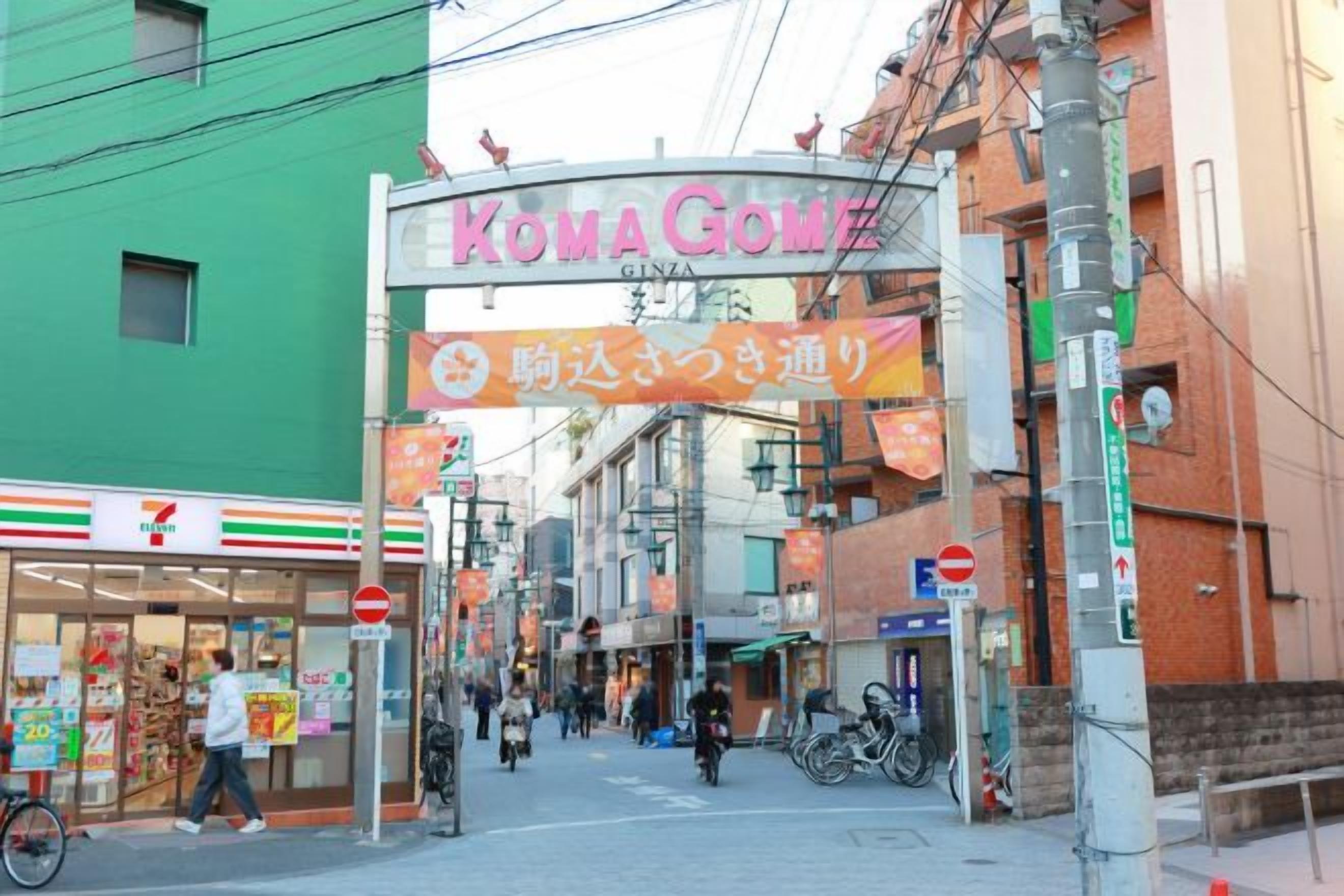 Une rue où se trouvent un magasin 7-Eleven et une enseigne KomaGome.