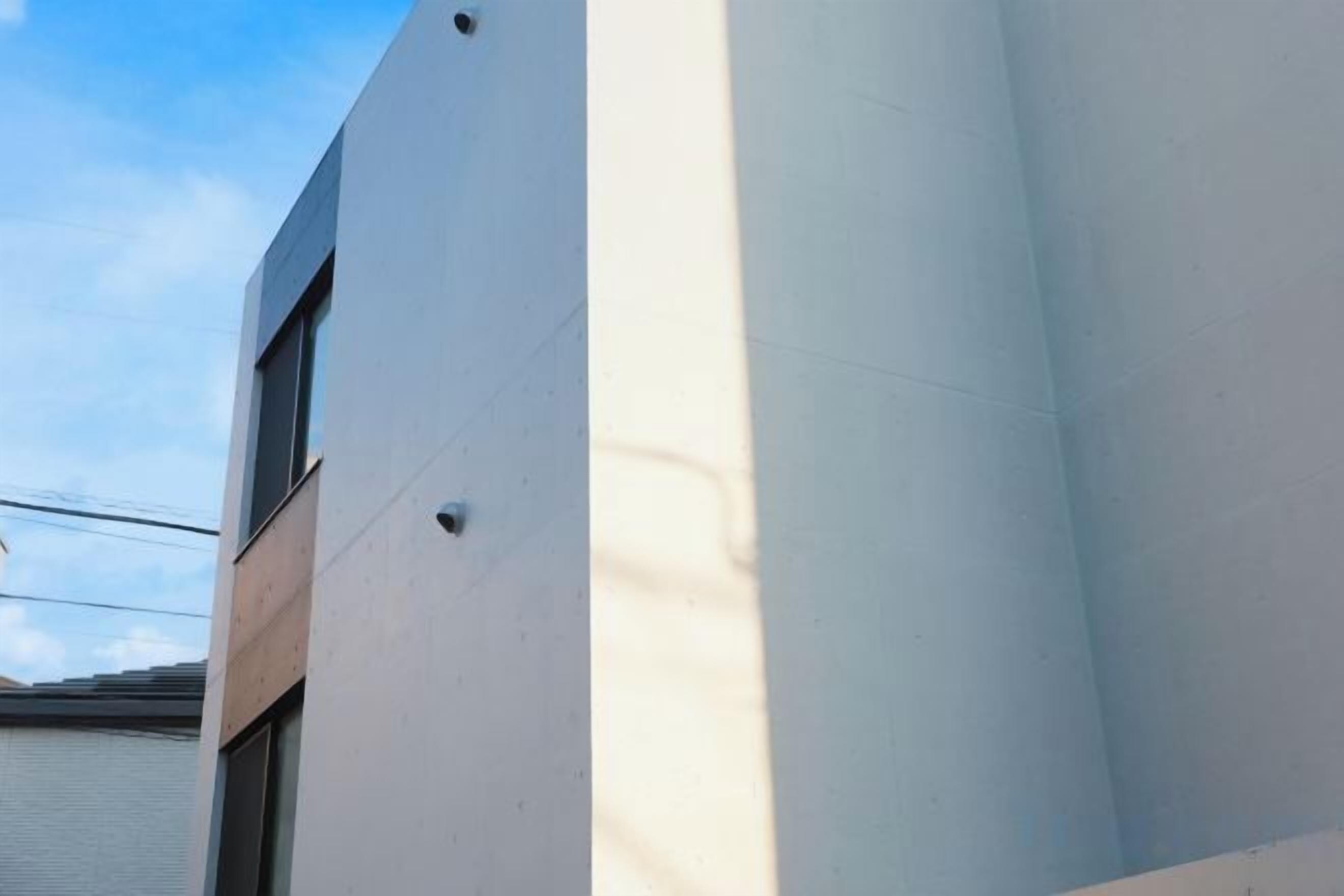 Un coin d’immeuble avec une façade blanche et une fenêtre.