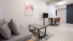 Een moderne woonkamer met een bank, een salontafel, een televisie en een eethoek.