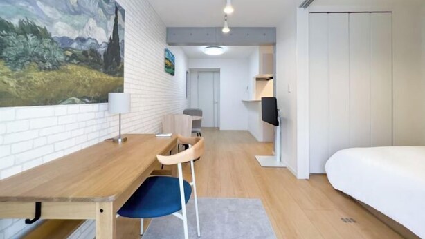 A modern room with a wooden desk, a blue chair, a bed, and a TV. - Blossom Terrace Ryogoku (Tokyo)