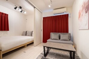 A compact room with a bed, a sofa, a small table, and a red curtain. - Blossom Terrace Ryogoku (Tokyo)