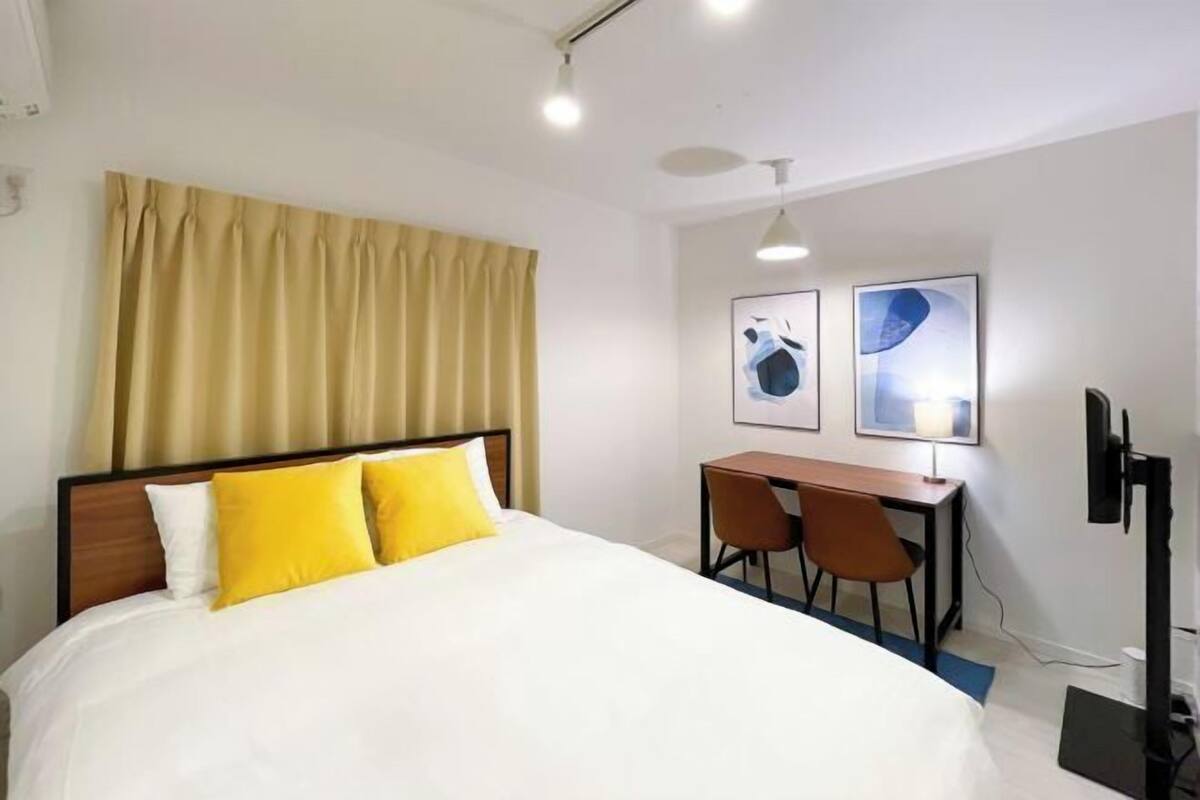 Habitación de hotel con cama, escritorio, dos sillas y televisión.