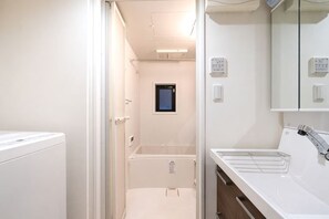 A bathroom with a shower, a sink, and a mirror. - Blossom Terrace Ryogoku (Tokyo)