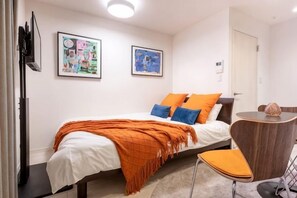 A bedroom with a bed, a chair, a small table, and two framed pictures on the wall. - Blossom Terrace Ryogoku (Tokyo)