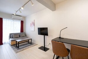 A modern living room with a sofa, coffee table, TV, and two chairs. - Blossom Terrace Ryogoku (Tokyo)