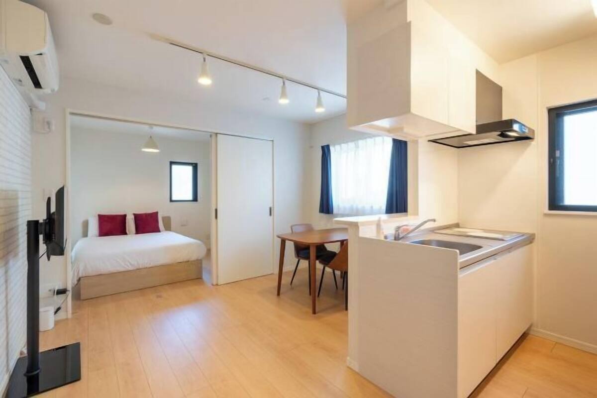 Una habitación de hotel compacta con cama, un pequeño comedor, kitchenette y baño.