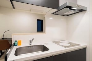 A modern kitchen with a stainless steel sink, a built-in stove, and black cabinets. - Blossom Terrace Ryogoku (Tokyo)