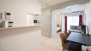 Een moderne keuken met een magnetron, een koffiezetapparaat en een kleine koelkast. Er is een eethoek met een tafel en stoelen.