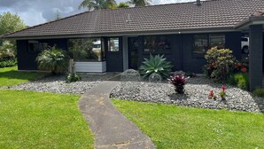 Une maison moderne avec un toit en tuiles, un porche abrité et un chemin de gravier menant à l’entrée.