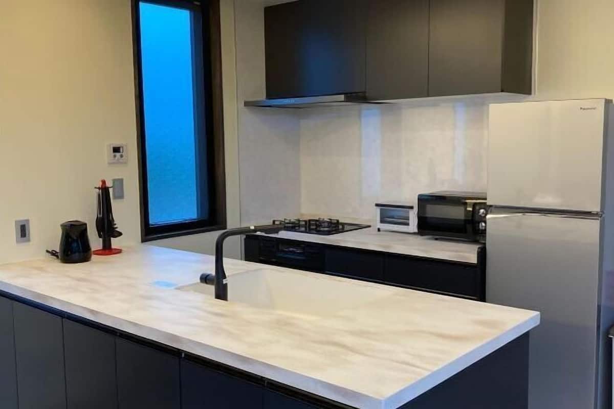 Una cucina moderna con isola centrale, forno a incasso, microonde e frigorifero.