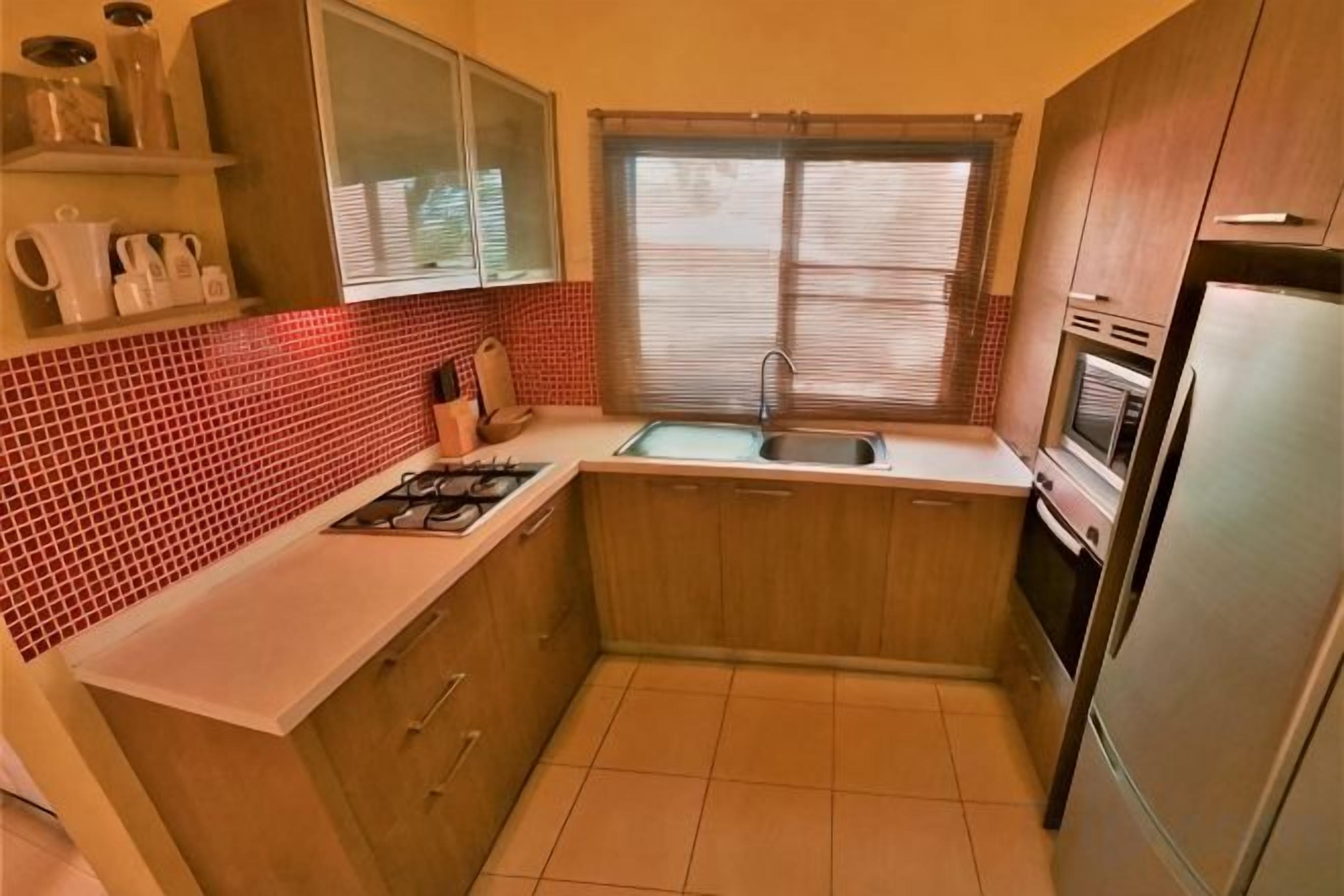 A compact kitchen with a gas stove, sink, oven, and refrigerator.