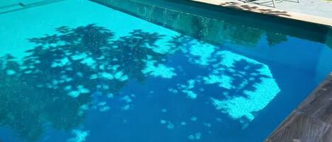 A swimming pool with a wooden deck and lounge chairs.