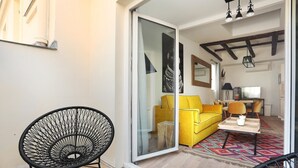 A modern living room with a yellow sofa, a black chair, and a dining area with a table and chairs.