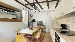 A modern kitchen with wooden beams, a dining area with a patterned rug, and a large mirror.