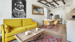 A bright yellow sofa in a living room with a tray table and two candles. A large framed picture is on the wall.