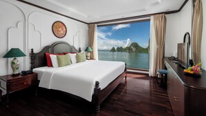 A spacious bedroom with a large bed, a nightstand, a dresser, and a view of a body of water. - Cycad Cruise (Bai Chay)