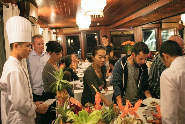 A group of people gathered around a table in a restaurant with wooden interiors and a chandelier.
