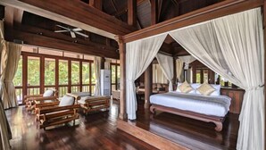 Ein geräumiges Zimmer mit einem großen Bett, Holzmöbeln und einem Deckenventilator.