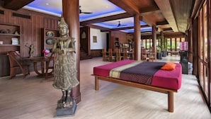 Ein geräumiges Zimmer mit einem großen Bett, Holzbalkendecke und einer Statue.