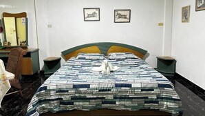 Una camera da letto con un letto, una sedia, una scrivania e uno specchio. Due quadri appesi alla parete.