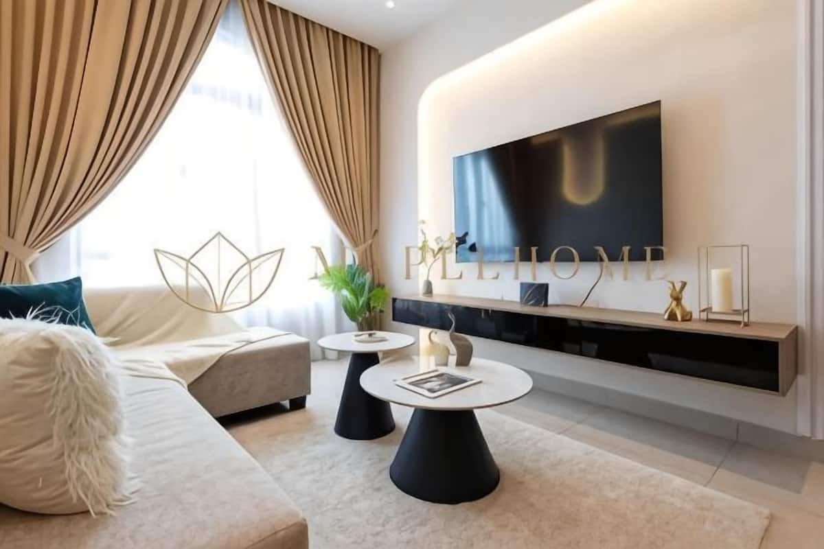 Een moderne woonkamer met een grote flatscreen televisie, een bank, een salontafel en een decoratieve plant.