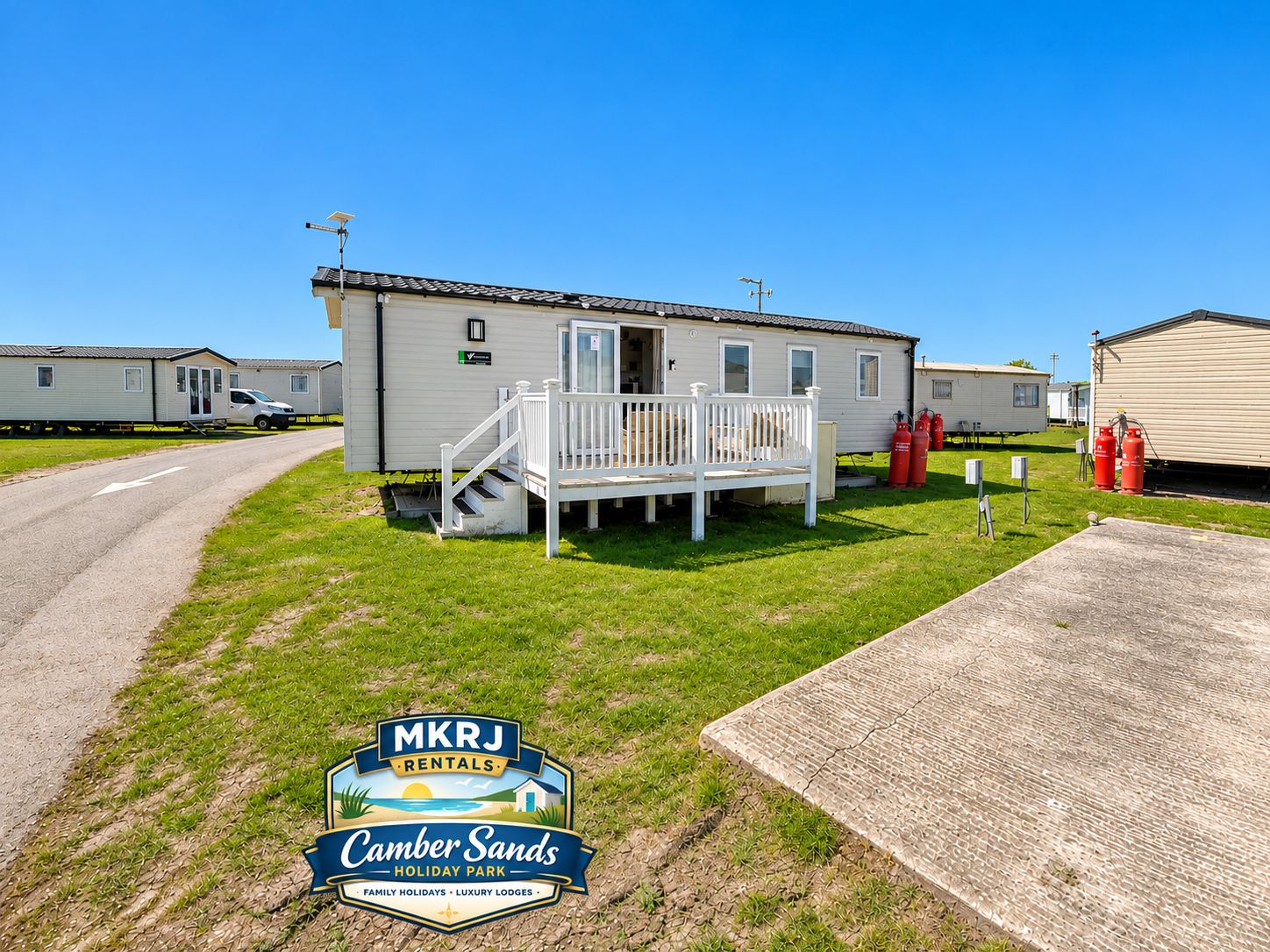A mobile home with a porch and steps, located in a grassy area with a clear sky.